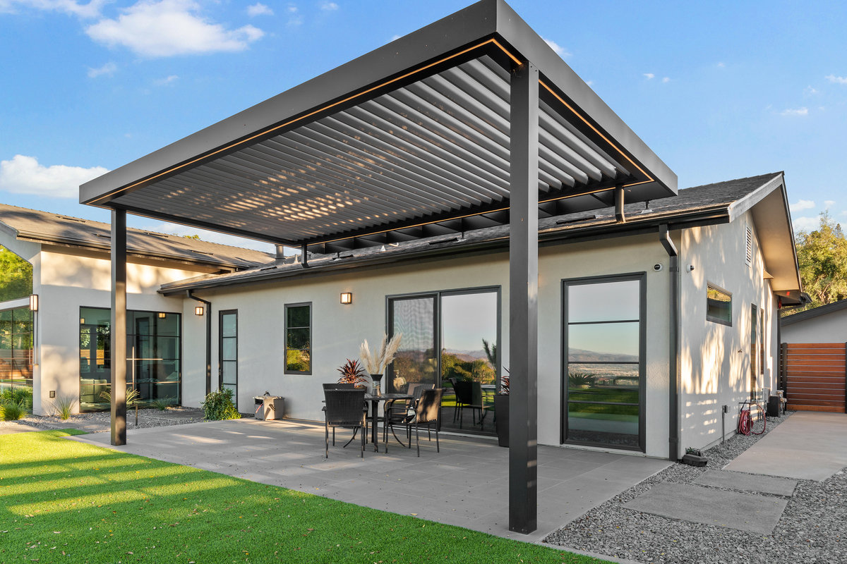 White aluminum louvered pergola with built-in lighting system covering outdoor patio dining area.
