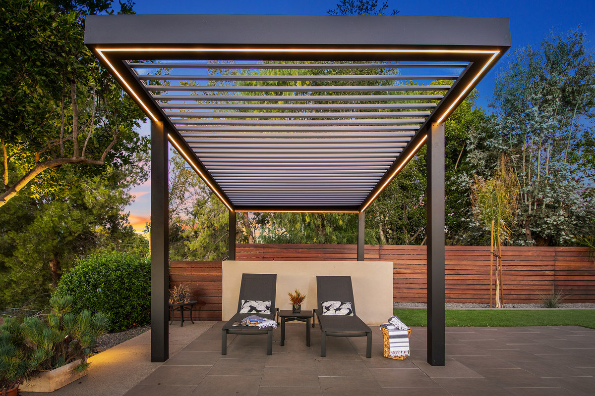 Smart louvered roof pergola with app-controlled louvers and built-in LED lighting covering backyard area.