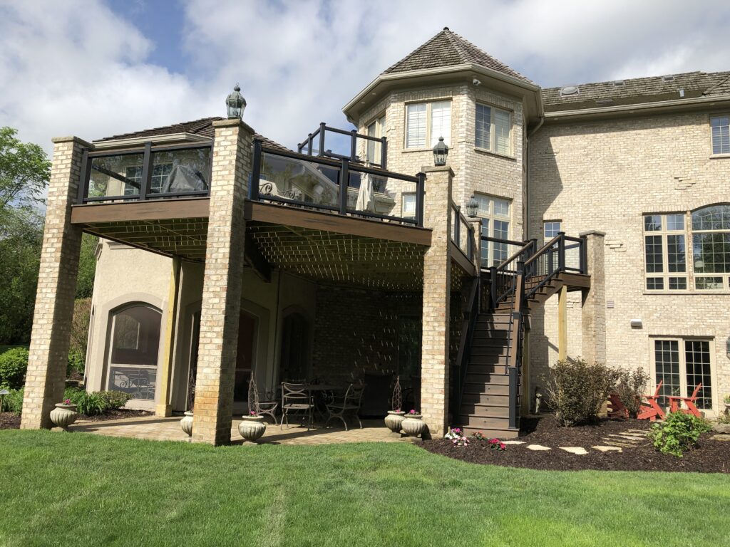 Newly built Trex deck with glass infill railings supported on brick pillars in Chicago suburbs IL.